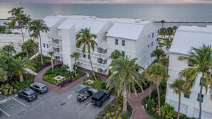 Een strandhotel met meerlaags gebouwen, een parkeerplaats en palmbomen.