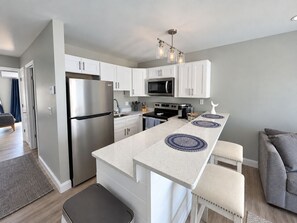 A modern kitchen with white cabinets, stainless steel appliances, and a central island with blue placemats.