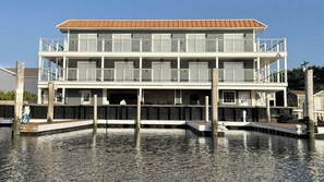 A multi-story waterfront building with balconies and a dock extending into the water.