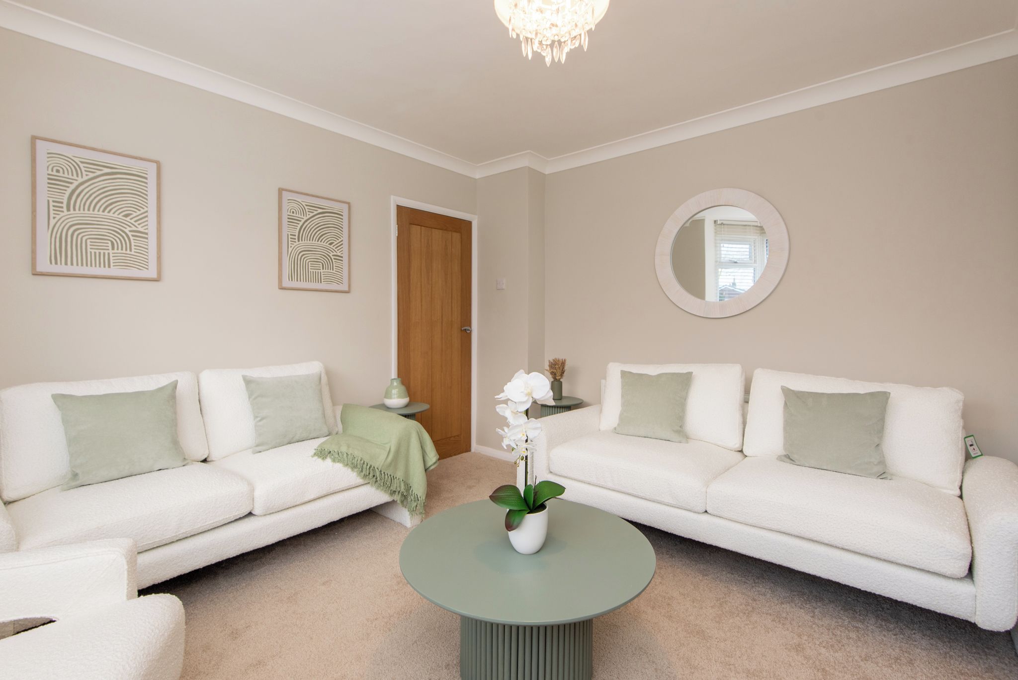 A living room with two white sofas, a round coffee table, and a wooden door.