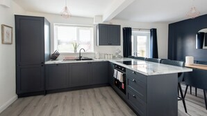 Una cocina moderna con armarios oscuros, una isla central e iluminación colgante.