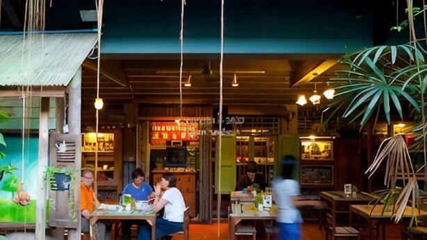 Un'area pranzo all'aperto con tavoli e sedie, una struttura in legno e piante pensili.