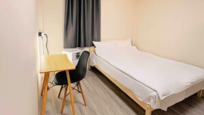 Una stanza piccola e ordinata con un letto, una scrivania e una sedia.