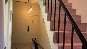 Una scala con gradini in legno e ringhiere nere, che conduce a una porta con maniglia.