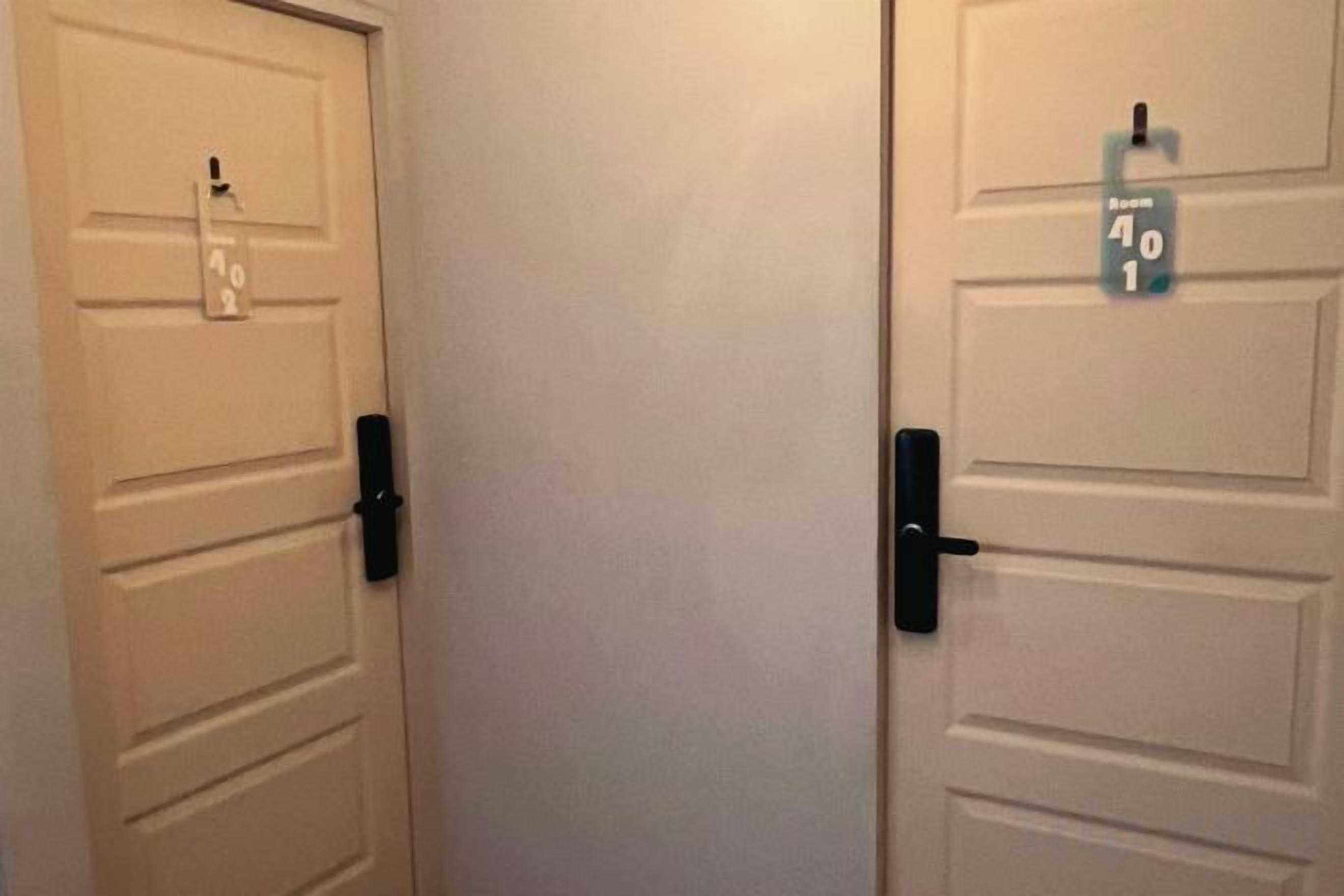 Two white doors with black handles and a small sign above each door.
