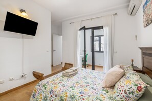 A bedroom with a bed, a TV mounted on the wall, a chair, a desk, and a window with curtains. - Holiday Villa 'Vera' with Mountain Views, Private Pool, and Wi-Fi (Playa Blanca)