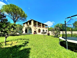A two-story building with a balcony, surrounded by a grassy lawn and trees. - Gîte 4/6p, 2 bedrooms, 2 bathrooms, heated outdoor pool, park, jacuzzi, trampoline (Mercuer)