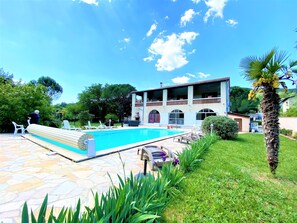 A pool area with lounge chairs and a building with a balcony. - Gîte 4/6p, 2 bedrooms, 2 bathrooms, heated outdoor pool, park, jacuzzi, trampoline (Mercuer)