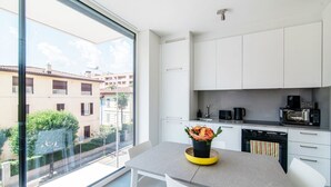 A modern kitchen with white cabinets, a gray countertop, and a view of the city through large windows. - A one-bedroom apartment for an excellent stay (FLAT IRON 7) (Viganello)