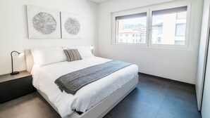 A modern bedroom with a bed, bedside tables, and artwork on the wall. - A one-bedroom apartment for an excellent stay (FLAT IRON 7) (Viganello)