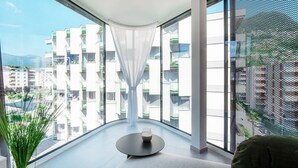 Una habitación moderna con ventanas amplias, una mesa redonda y vistas a una zona residencial.
