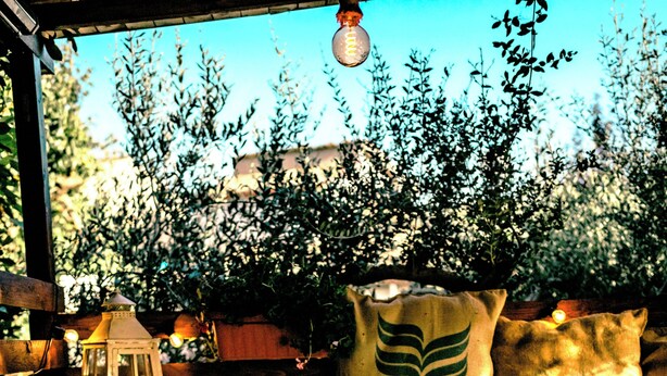 A hot tub with a wooden deck, surrounded by potted plants and a lantern. - THE STONE DIMORA - Madonie Suite & Garden SPA-Exclusive Villa & Private Park  (Blufi)