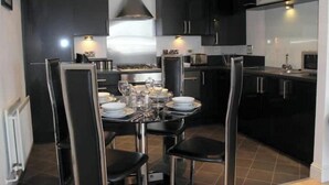 A modern kitchen with dark cabinetry, a central island with dining setup, and built-in appliances. - Central 2-bedroom flat with private parking in Aberdeen (Aberdeen)