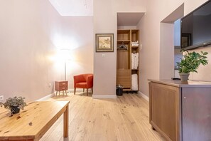 A modern room with a wooden floor, a dining table, a red chair, a wardrobe, and a TV mounted on the wall. - Stylish Aparthotel | 1 Room+Lounge by Mariahilfer (Vienna)