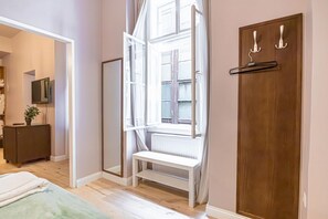 Une pièce avec une porte en bois, un banc, un radiateur, une fenêtre et un téléviseur fixé au mur.