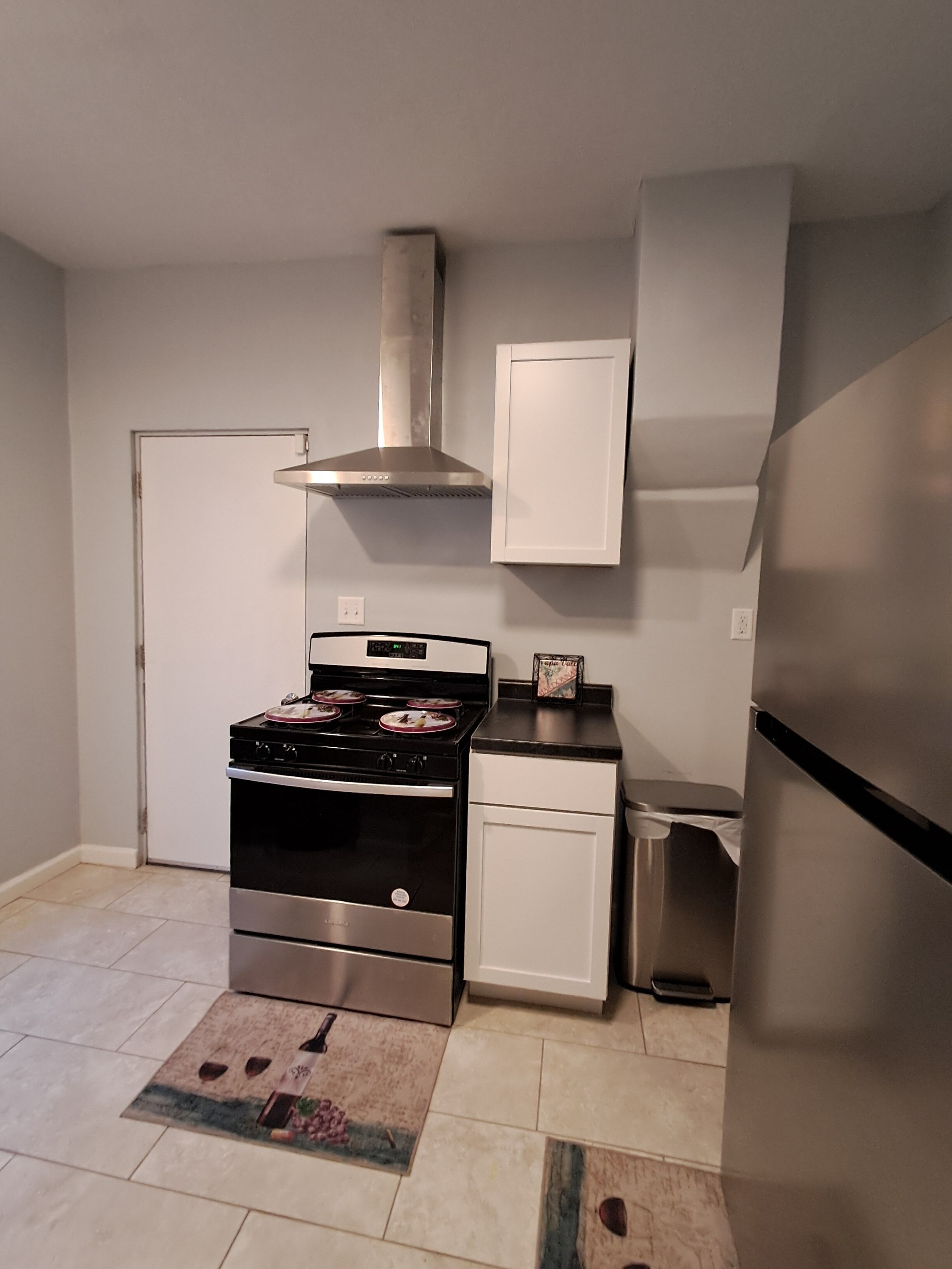 A compact kitchen with a stove, oven, and a stainless steel range hood.