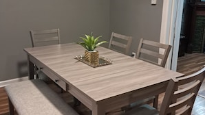 Une table à manger avec six chaises, un banc et une petite plante servant de décoration centrale.