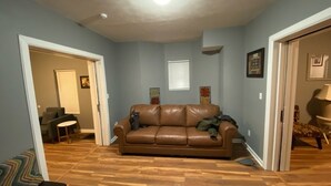 Un salon avec un canapé en cuir marron, un plancher en bois et des murs bleu clair.