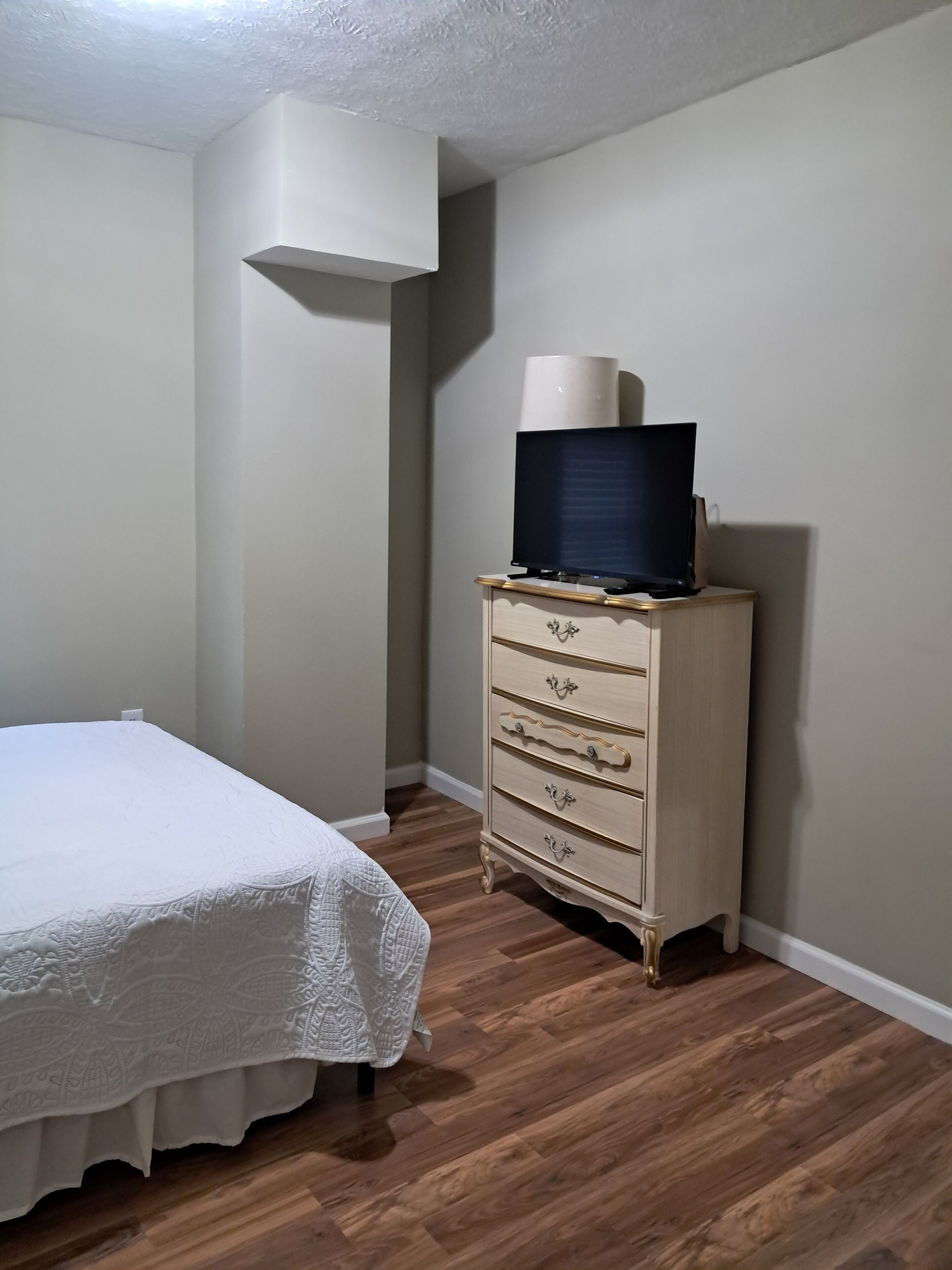 Een slaapkamer met een bed, een dressoir en een televisie erboven.