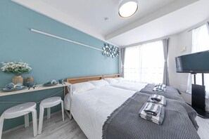 Ein Schlafzimmer mit Bett, Schreibtisch, zwei Stühlen, einem Fernseher und einem Fenster.