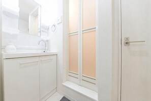 A bathroom with a white sink, mirror, and cabinets. - Tsubaki　202 (Tokyo)