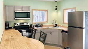 Una cocina moderna con una mesa de comedor de madera, electrodomésticos de acero inoxidable y paredes de color verde claro.