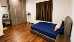 Un dormitorio con cama, mesita de noche, armario y ventilador de pie.