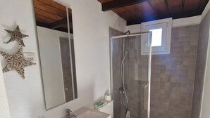 A bathroom with a wooden ceiling, a white sink, a toilet, and a glass shower enclosure. - Apartment 'Casa Deco' with Mountain Views, Wi-Fi and Air Conditioning (Los Llanos)