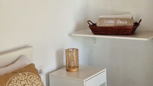 A bedroom with a bed, a nightstand, a lamp, and two shelves with baskets labeled 'Casa Deco'. - Apartment 'Casa Deco' with Mountain Views, Wi-Fi and Air Conditioning (Los Llanos)