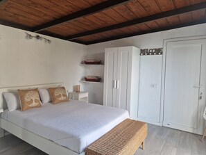 A bedroom with a bed, a bench, a wardrobe, and shelves with baskets.