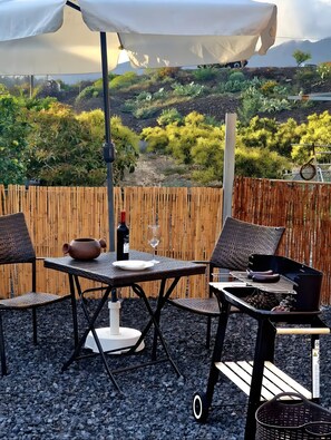 Une terrasse extérieure avec une table, des chaises, un barbecue et une vue sur un paysage montagneux.