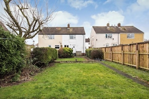 A residential area with two houses, a wooden fence, and a well-maintained lawn.