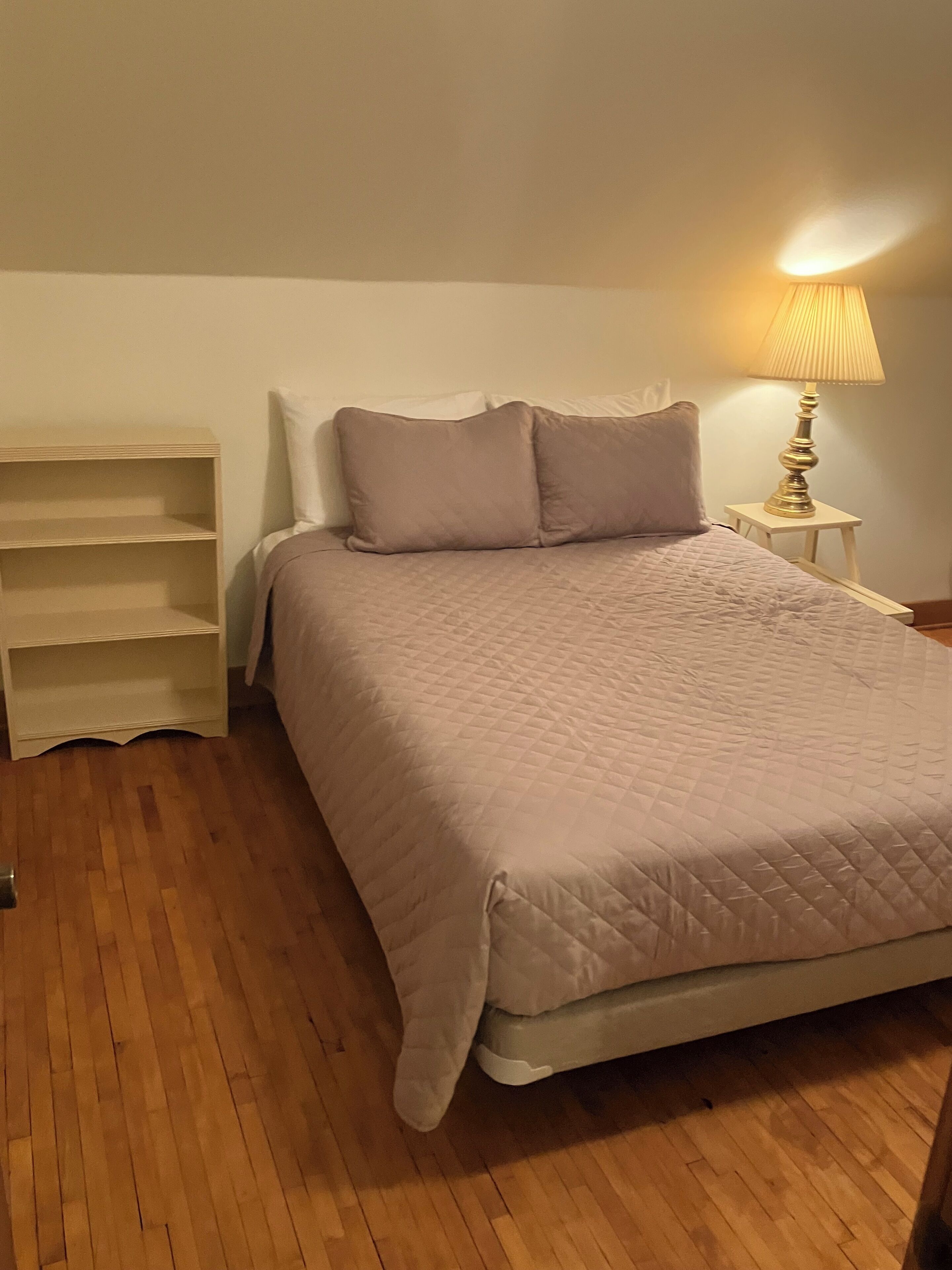 Une chambre à coucher comprenant un lit, une table de chevet, une lampe et une bibliothèque intégrée.