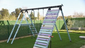 A playground with a slide, climbing ladder, and swings.
