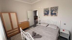 A bedroom with a bed, a wardrobe, a nightstand, and two paintings on the wall.