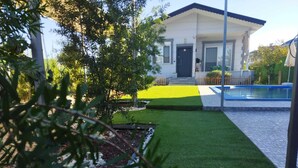 A house with a front yard, a swimming pool, and a small garden area.