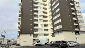 A multi-story residential building with balconies and a parking area in front. - Trabajo y Relax VIP en La Serena (La Serena)