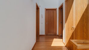 Un pasillo con puertas de madera, un banco y un interruptor de luz en la pared.