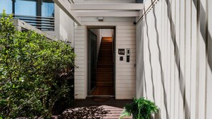 Un sendero estrecho que conduce a una escalera de madera con una puerta marcada 'B18' y un buzón.