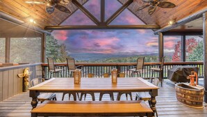 A wooden deck with a table and chairs, a view of the mountains, and a decorative ceiling fan. - Heated Pool, Spa, Theater & Mountain Views, 6 King en suites – Sleeps 20 (Mineral Bluff)