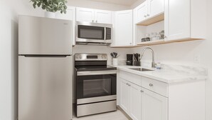 A modern kitchen with stainless steel appliances, white cabinetry, and a marble countertop. - 1/1 Relaxing Retreat in Sunny Bonita Springs (Bonita Springs)