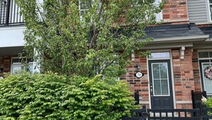 A two-story building with a brick facade, a black door, and a mailbox. - Cozy Whitby Shores Townhome| Marina and Free Parking (Whitby)