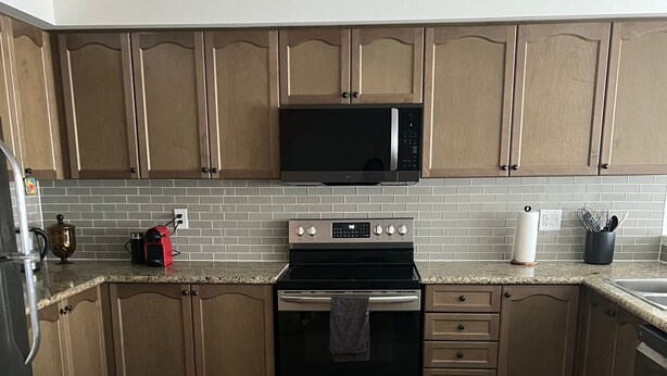 A kitchen with wooden cabinets, a microwave, an oven, and a sink. - Cozy Whitby Shores Townhome| Marina and Free Parking (Whitby)