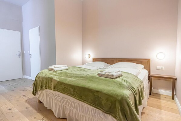 A bedroom with a bed, two bedside tables, and a door.
