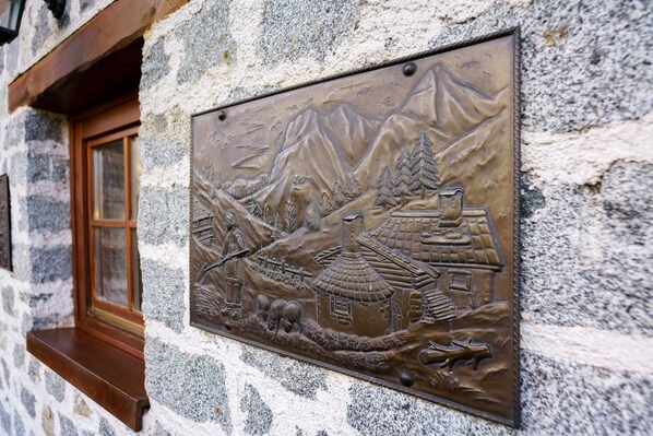 A wall-mounted plaque with a mountain scene, a traditional building, and a wooden window frame.