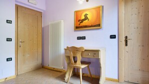 Een kamer met een houten bureau, een stoel, een radiator en twee deuren.