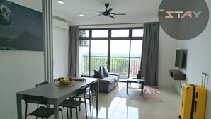 Sala moderna com área de jantar, janelas amplas, ventilador de teto e uma mala amarela.