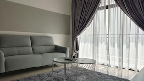 Uma sala de estar moderna com um sofá cinzento, uma mesa de centro redonda e cortinas translúcidas.