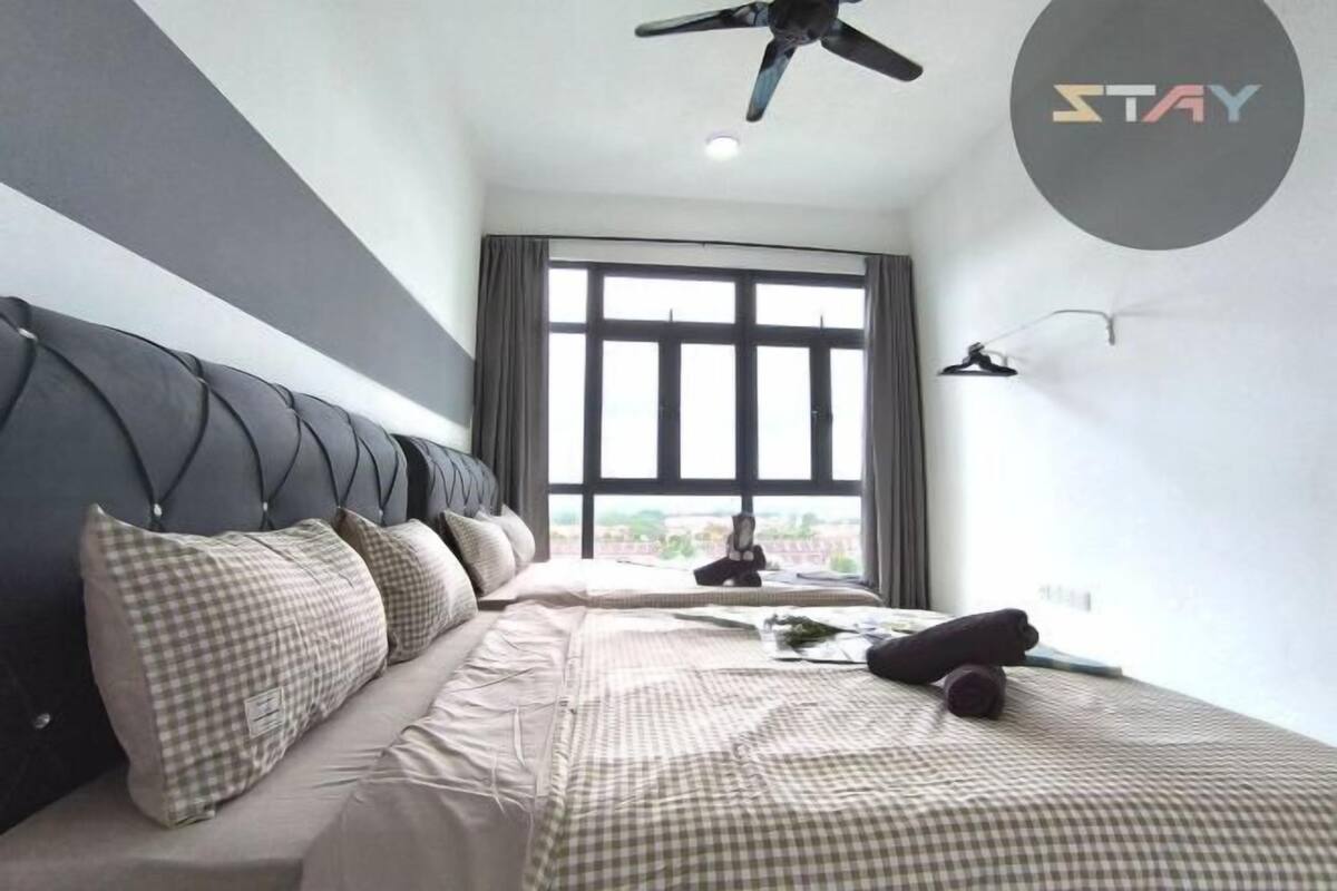 A modern hotel room with a large bed, a ceiling fan, and a view of the city through large windows.