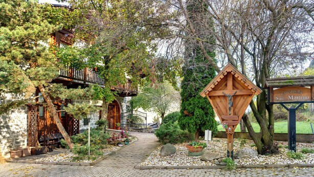 Ein Kopfsteinpflasterweg führt zu einem Holzhaus mit dem Schild 'Locanda San Martino'.